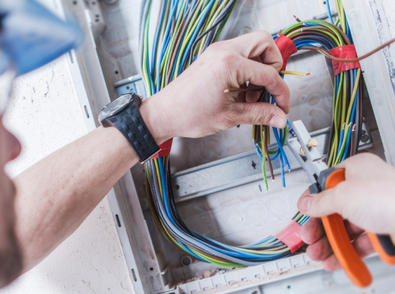 Electrician stripping and connecting color-coded wires with pliers